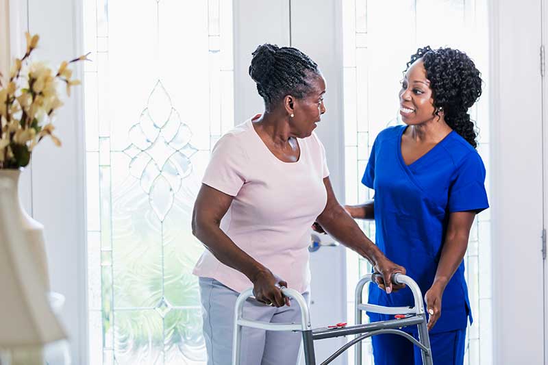Home health aide helping senior with walker in South Carolina